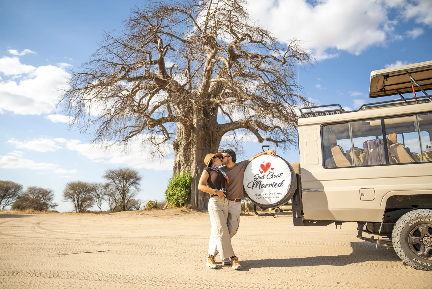 Couple beside a giant baobab tree and their safari vehicle